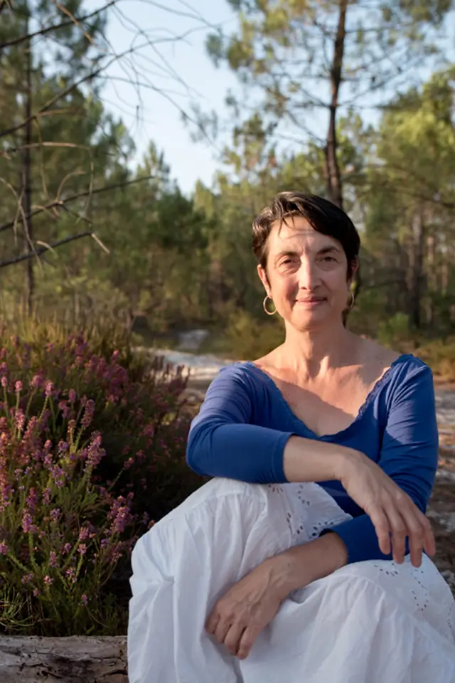 Isabelle Bertone, coach en évolution financière, assise en pleine nature.